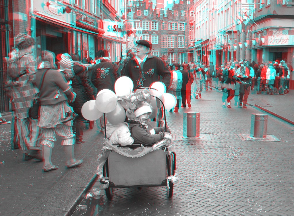 Анаглиф - Мужчина катит по городу тележку с детьми и с воздушными шариками Анаглиф - Мужчина катит по городу тележку с детьми и с воздушными шариками